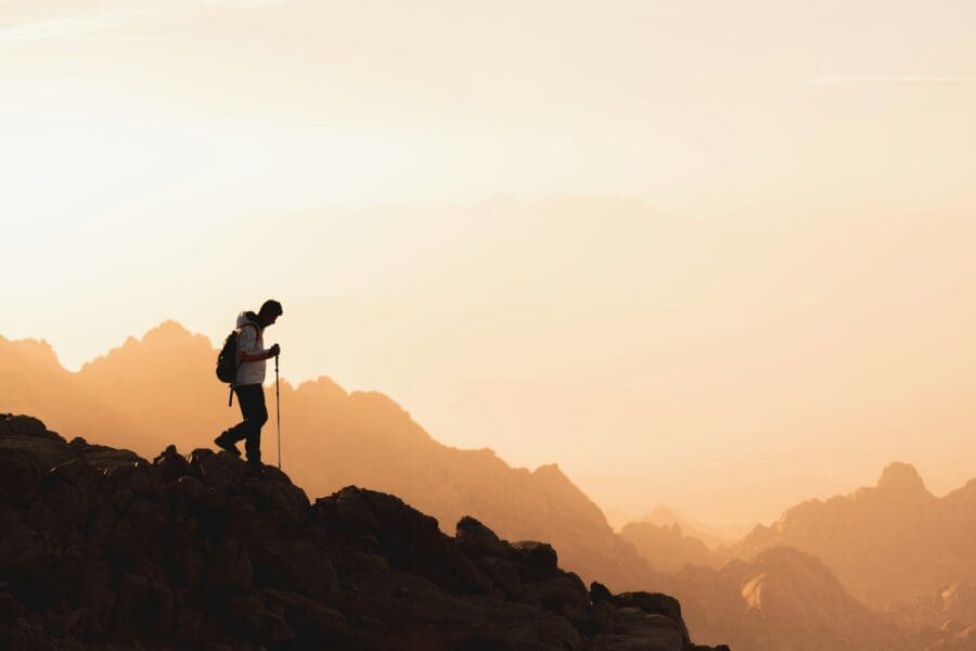 The silhouette of a man rucking across a mountain at sunset